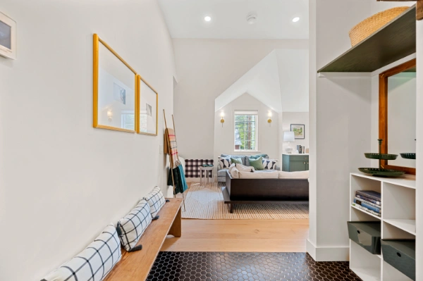 Interior entry hall with built-in bench seating, black hex tile flooring, and view into a bright living space beyond